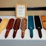 A vending event display showcasing handcrafted wooden impact implements, including paddles and canes, neatly arranged on covered tables.